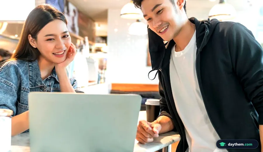 Đôi bạn trẻ đang ngồi tại quán cà phê và cùng nhau quan sát thông tin hiển thị trên màn hình laptop.