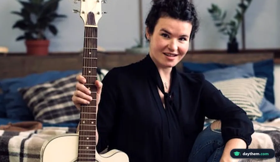 Một phụ nữ mỉm cười đang tự học đàn guitar tại phòng riêng