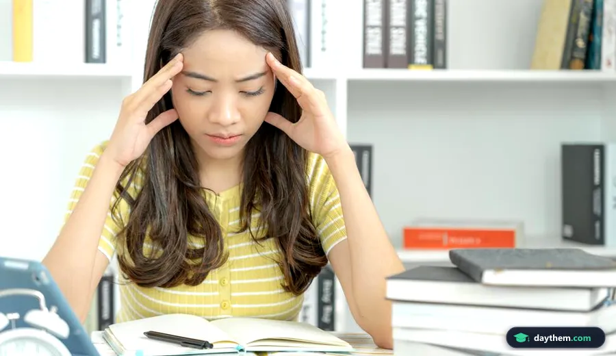 Nữ sinh viên châu Á ôm đầu căng thẳng, lo âu trước sách vở và tài liệu khi học tập